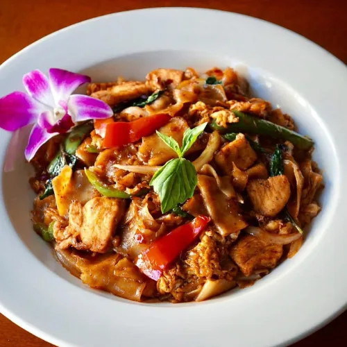 Drunken Noodles - Stir-fried wide flat noodle with egg, carrots, baby corn, green pepper and Thai basil leaves.