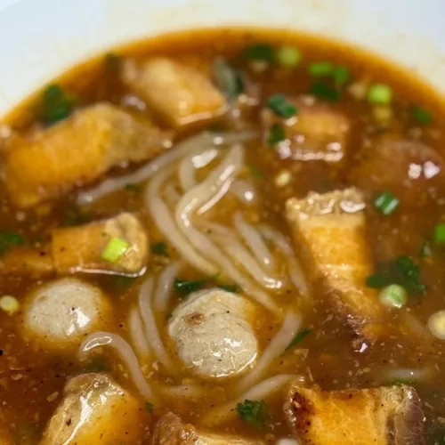 Khao Piak - Homemade rice noodle in chicken broth, garnished with green onions, cilantro, topped with fried onions and garlic.